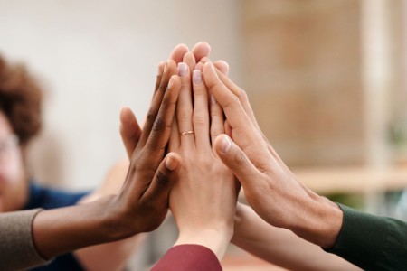 Close up on hands meeting for a high five from a diverse group of people